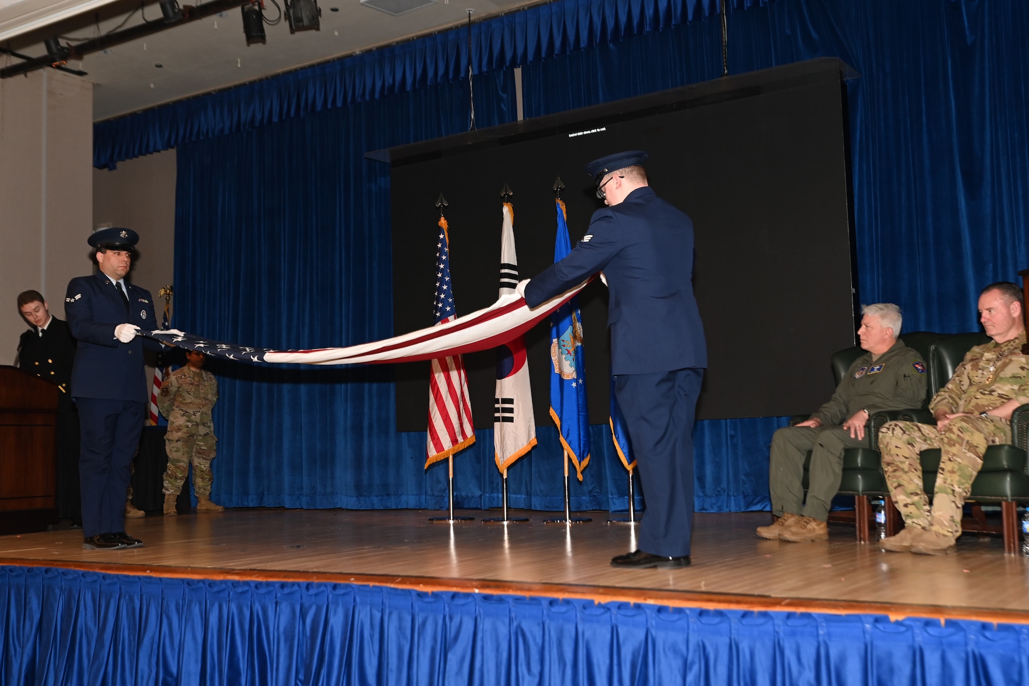 Members of the Osan Honor Guard fold a U.S. flag during the retirement ceremony of Maj. Gen. Daniel Heires, Mobilization Assistant to the Commander, Air Component Command, United Nations Command; Commander, Air Component Command, Combined Forces Command; and Commander, 7th Air Force, right, at Osan Air Base, Republic of Korea, March 15, 2024.