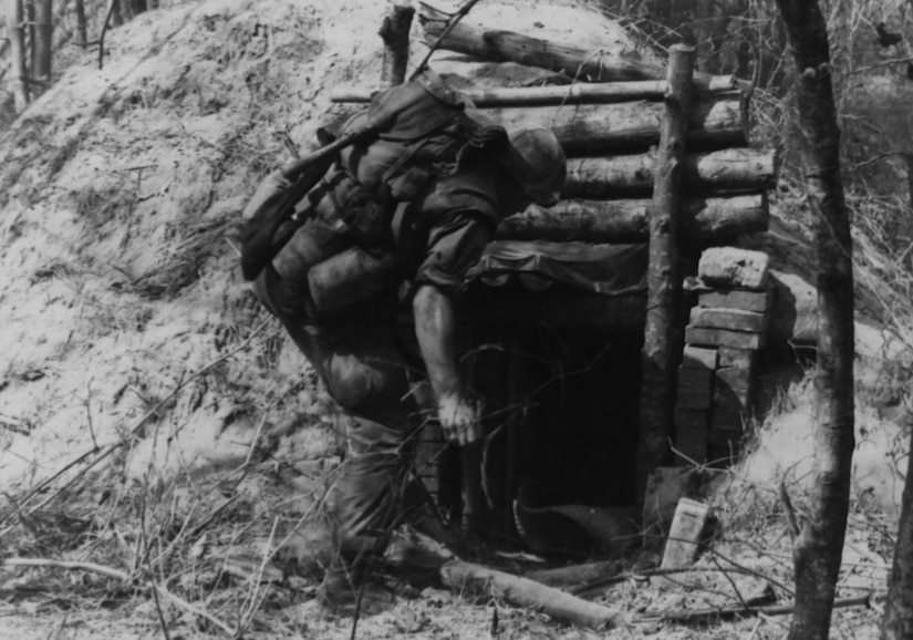 A man starts to put his foot into a small tunnel.