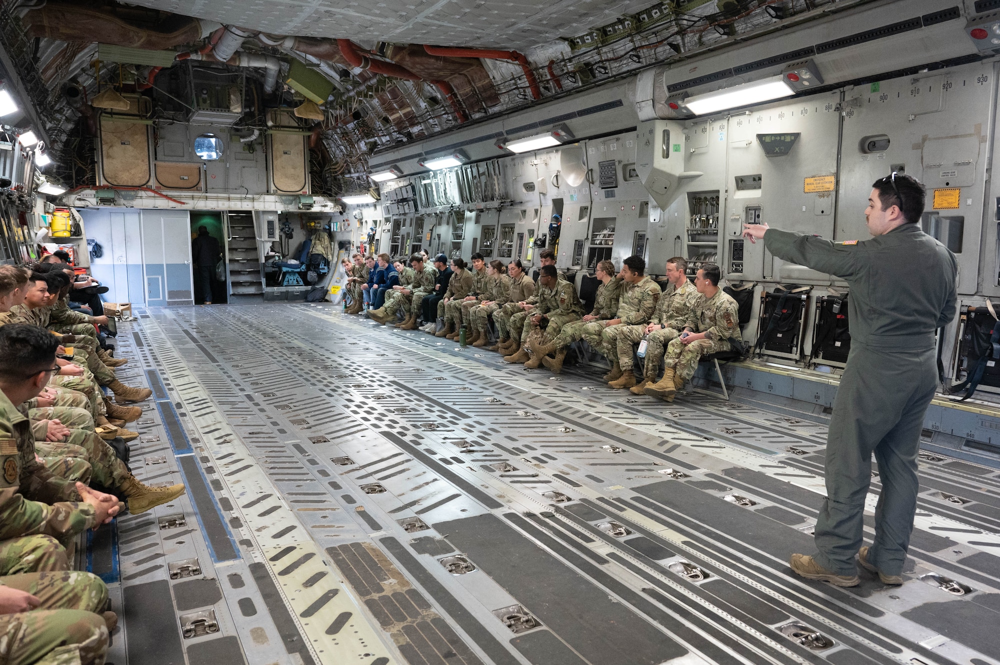 U.S. Air Force Staff Sgt. Jacob Villaruel, 58th Airlift Squadron loadmaster instructor, gives a safety brief to Air Force ROTC cadets and first term Airmen on a C-17 Globemaster III orientation flight at Altus Air Force Base, Oklahoma, March 15, 2024. The cadets and Airmen were exposed to the capabilities of the aircraft and daily operations of aircrew. (U.S. Air Force photo by Airman 1st Class Heidi Bucins)