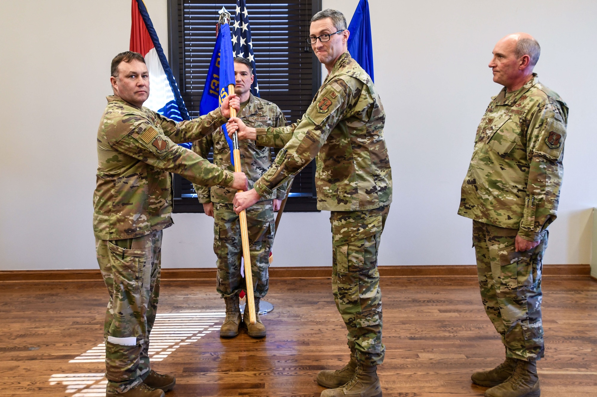 U.S. Air Force Airmen in OCP pattern uniforms pass a guidon flag during a change of command ceremony.