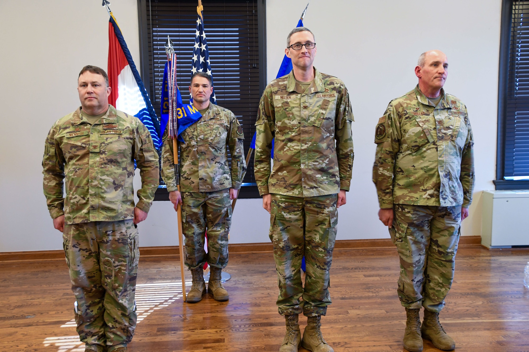 Four U.S. Air Force Airmen in OCP pattern uniforms stand at attention during a ceremony