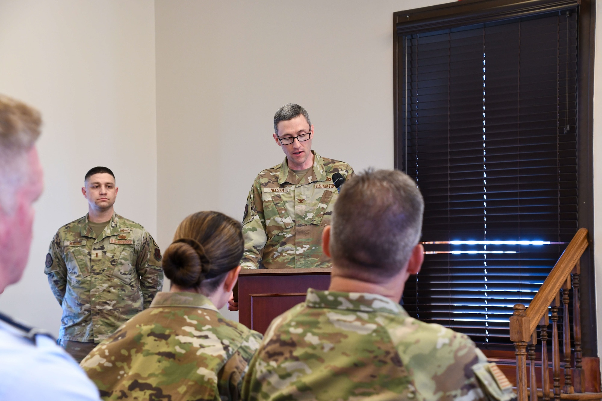 U.S. Air Force Airman in OCP pattern uniform stands at a lectern while giving a speech.