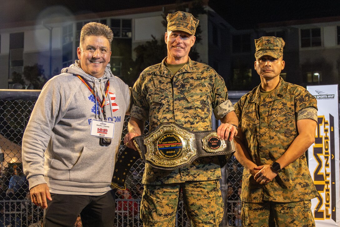 U.S. Marine Corps Colonel Patrick Byrne (center), the Commanding Officer of School of Infantry-West and Sergeant Major Damian Rodriguez (right), the Sergeant Major of School of Infantry-West, are presented with a championship belt during a Mixed Martial Arts Fight Night held at the School of Infantry-West parade deck at Marine Corps Base Camp Pendleton, California on March 15, 2024.  The MMA Fight Night consisted of amateur fighters going head-to-head in eight sanctioned bouts.  This event was coordinated by Marine Corps Community Services Camp Pendleton to promote base cohesion, increase morale, provide entertainment, and to prioritize quality of life for Marines, Sailors, and families. (U.S. Marine Corps photo by Lance Cpl. Mhecaela J. Watts)