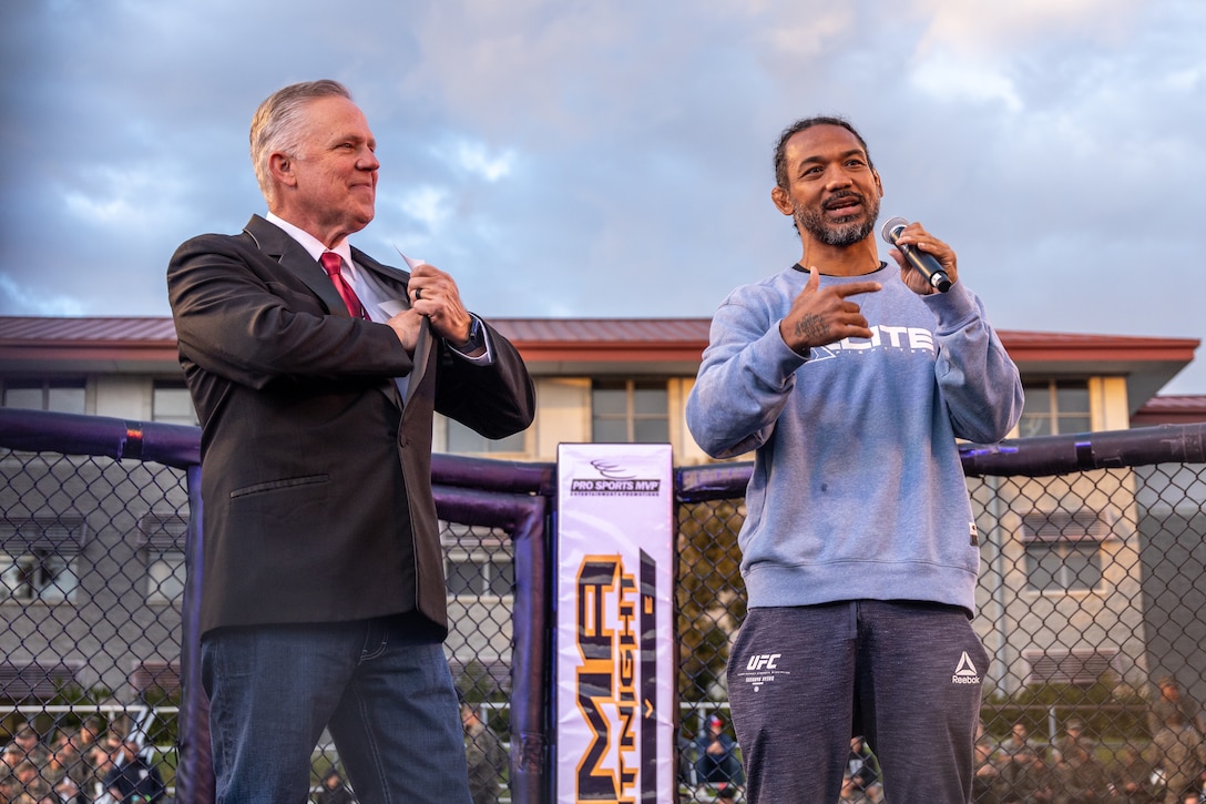 Mike Hart, left, a ring announcer, and Benson Henderson, the guest of honor and former professional mixed martial artist, deliver remarks during an MMA Fight held at the School of Infantry-West parade deck at Marine Corps Camp Pendleton, California, March 15, 2024. The MMA Fight Night consisted of amateur fighters going head-to-head in eight sanctioned bouts. This event was coordinated by Marine Corps Community Services Camp Pendleton to promote base cohesion, increase morale, provide entertainment, and to prioritize quality of life for Marines, Sailors, and families. (U.S. Marine Corps photo by Lance Cpl. Mhecaela J. Watts)
