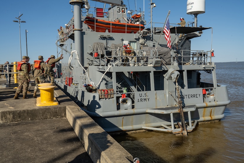 Soldiers handle lines aboard a military vessel.