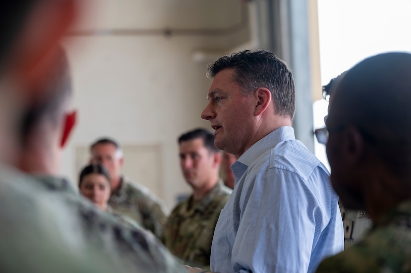 A civilian speaks with service members in uniform.