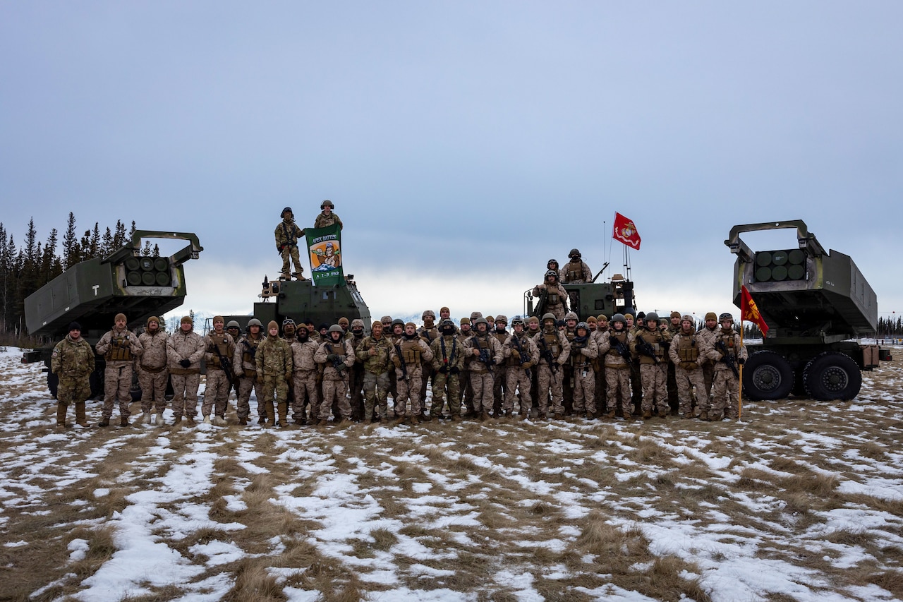 Dozens of Marines and soldiers pose for a photo in snowy environment.