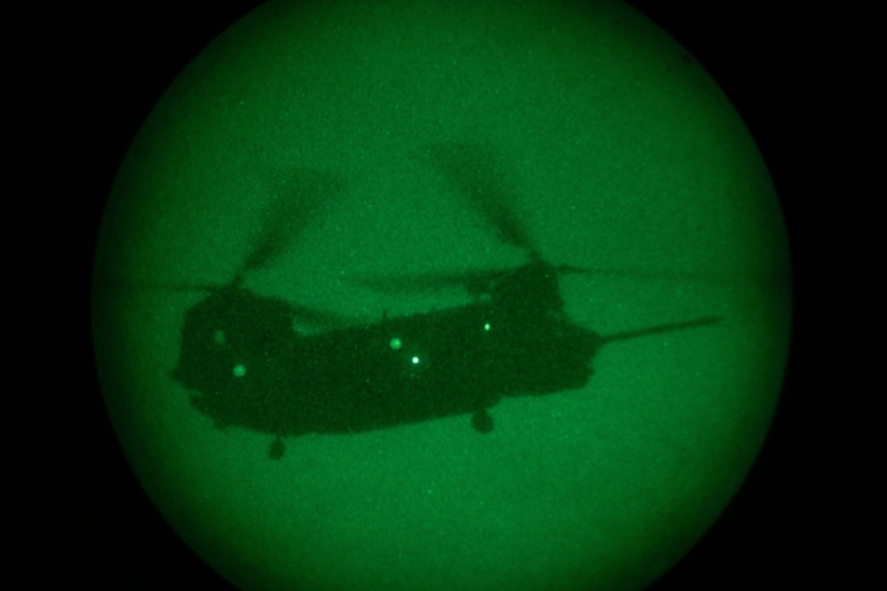 A helicopter flies as seen through night vision lens.