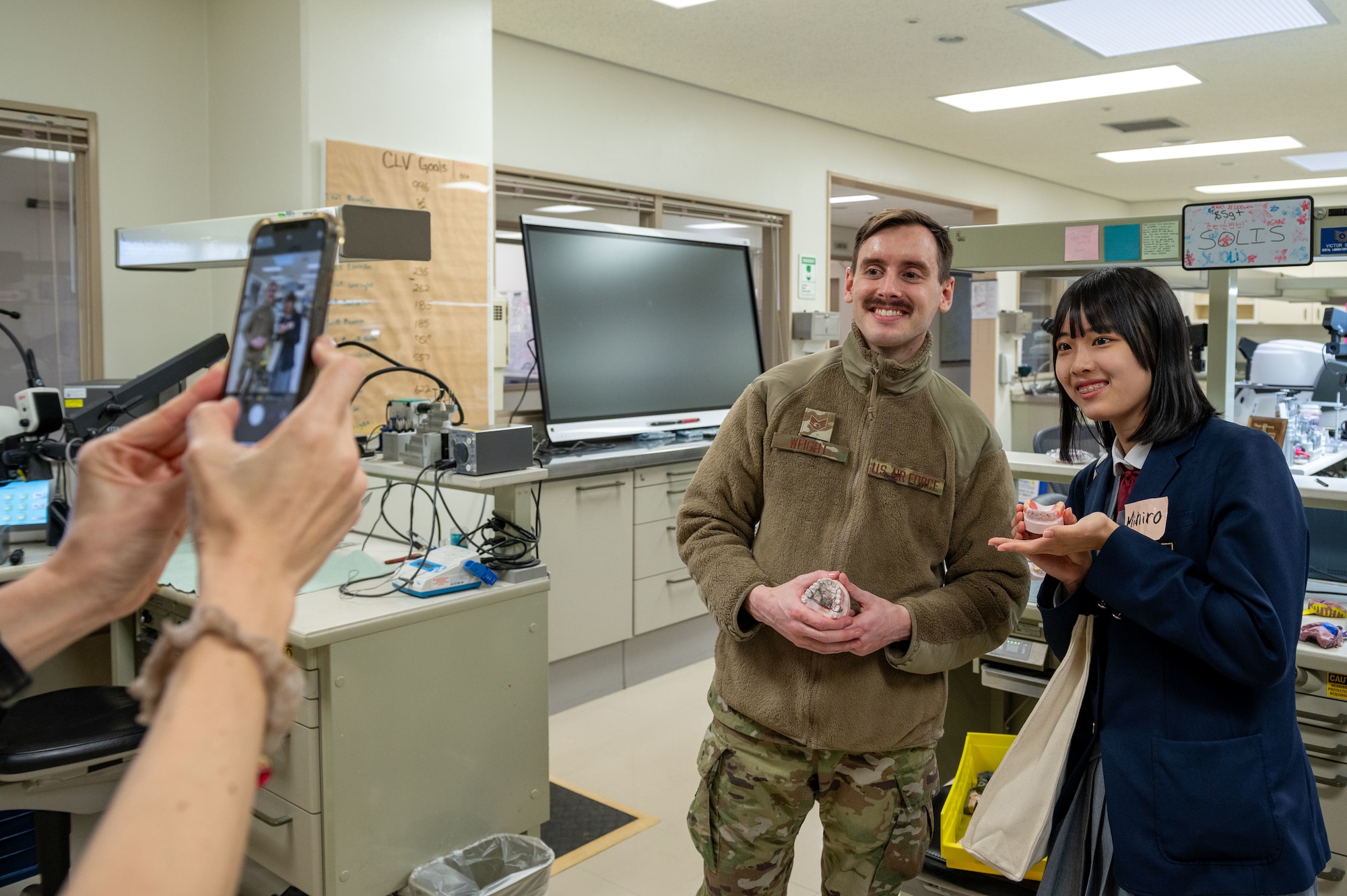 U.S. Air Force Staff Sgt. Brandon Weight, left, 18th Dental Squadron non-commissioned officer in charge of the regional dental lab logistics, and an Okinawan student pose for a photo inside of the dental lab