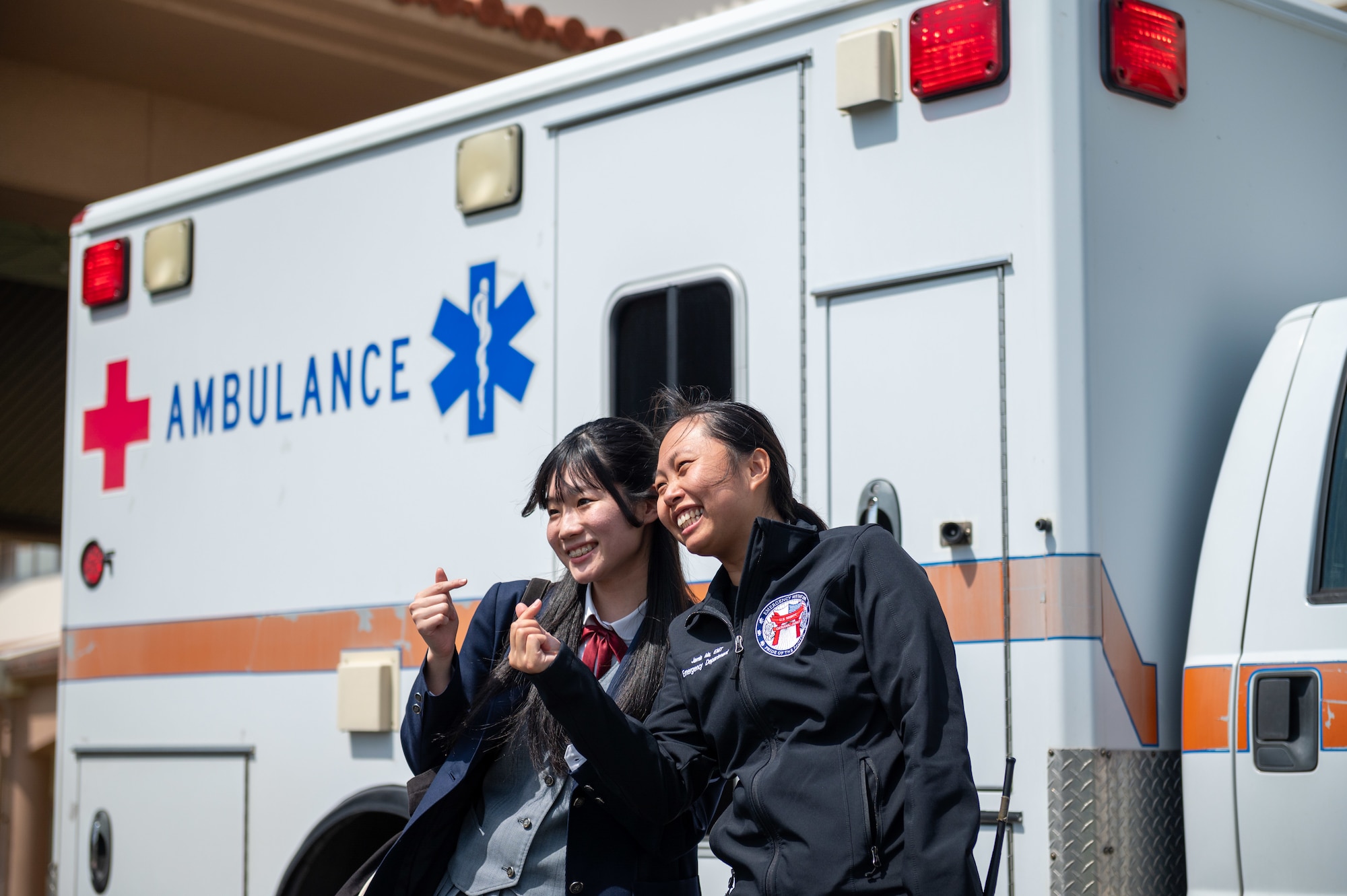 U.S. Air Force Staff Sgt. Jamie Ma, right, 18th Medical Group aerospace medical technician, takes a photo with an Okinawan student in front of an ambulance