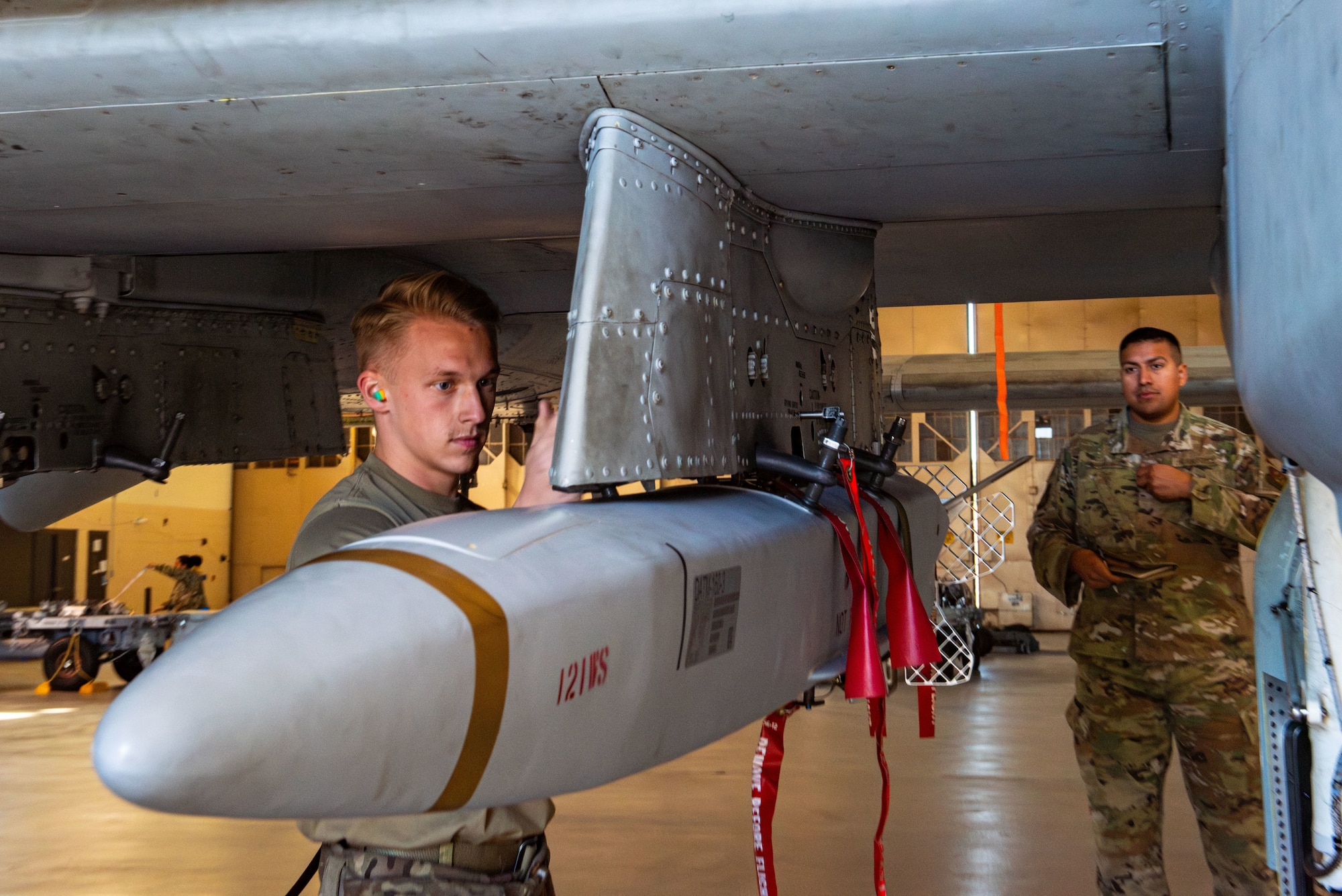 U.S. Air Force Airman 1st Class Kyler Stenke, 74th Fighter Generation Squadron load crew member, tightens bolts to secure a Miniature Air-Launched Decoy onto an A-10C Thunderbolt II at Moody Air Force Base, Georgia, Feb. 14, 2024. A MALD is used in combat to draw enemy defense weaponry away from aerial forces, allowing aircraft to move further into enemy territory more safely. (U.S. Air Force photo by Airman 1st Class Sir Wyrick)