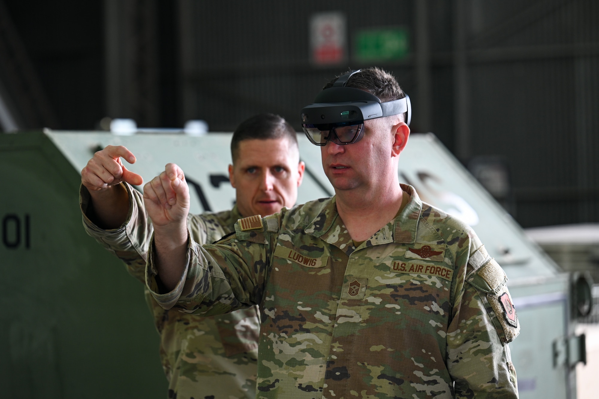 Chief Master Sgt. Louis Ludwig, right, 86th Airlift Wing command chief, is guided by Senior Master Sgt. Anthony Sewejkis, left, 725th Air Mobility Squadron maintenance superintendent, for a HoloLens showcasing during Exercise Rising Phoenix, Feb. 7,2024, at Morón Air Base, Spain.