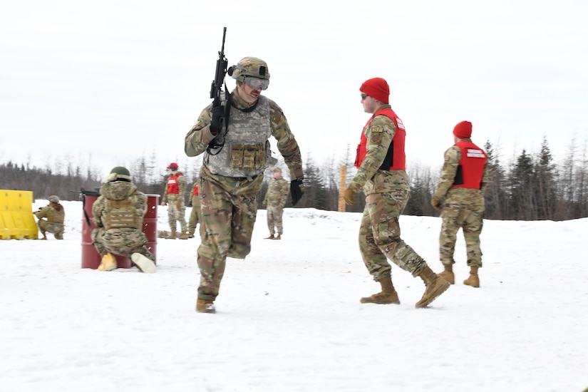 Airmen run, stand and kneel in the snow during a training exercise.