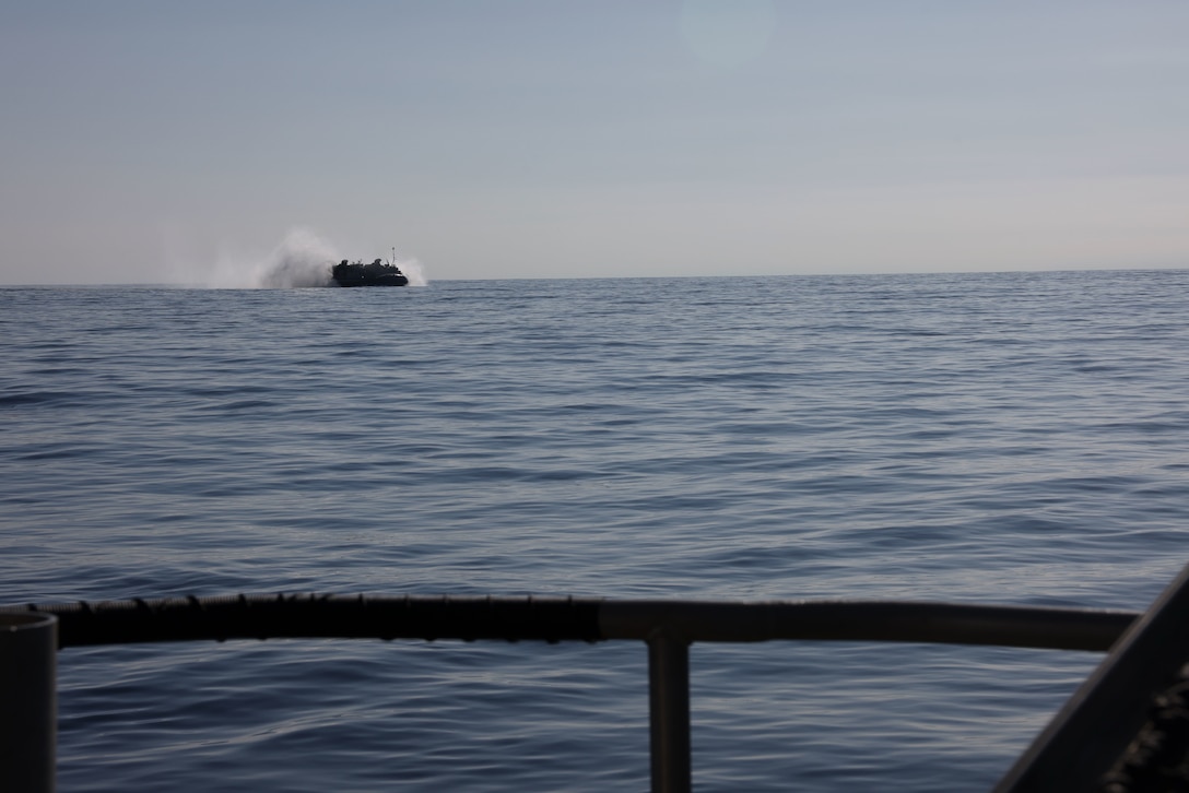 A U.S. Navy Landing Craft, Air Cushion assigned to Assault Craft Unit 5, transports a tractor, rubber-tired, articulated steering, multi-purpose vehicle and a joint light tactical vehicle, both assigned to Marine Wing Support Squadron 373, Marine Air Control Group 38, 3rd Marine Aircraft Wing, from San Clemente Island to Camp Pendleton, California, Feb. 28, 2024.  ACU 5 helped transport 835,000 pounds of equipment across 58 nautical miles in support of MWSS-373's Strategic Mobility Exercise (STRATMOBEX) II. During STRATMOBEX II, MWSS-373 demonstrated mastery of scalable air-ground support such as expeditious airfield damage repair, forward arming and refueling, integrated engineering, and explosive ordnance disposal operations. (U.S. Marine Corps photo by Lance Cpl. Samantha Devine)