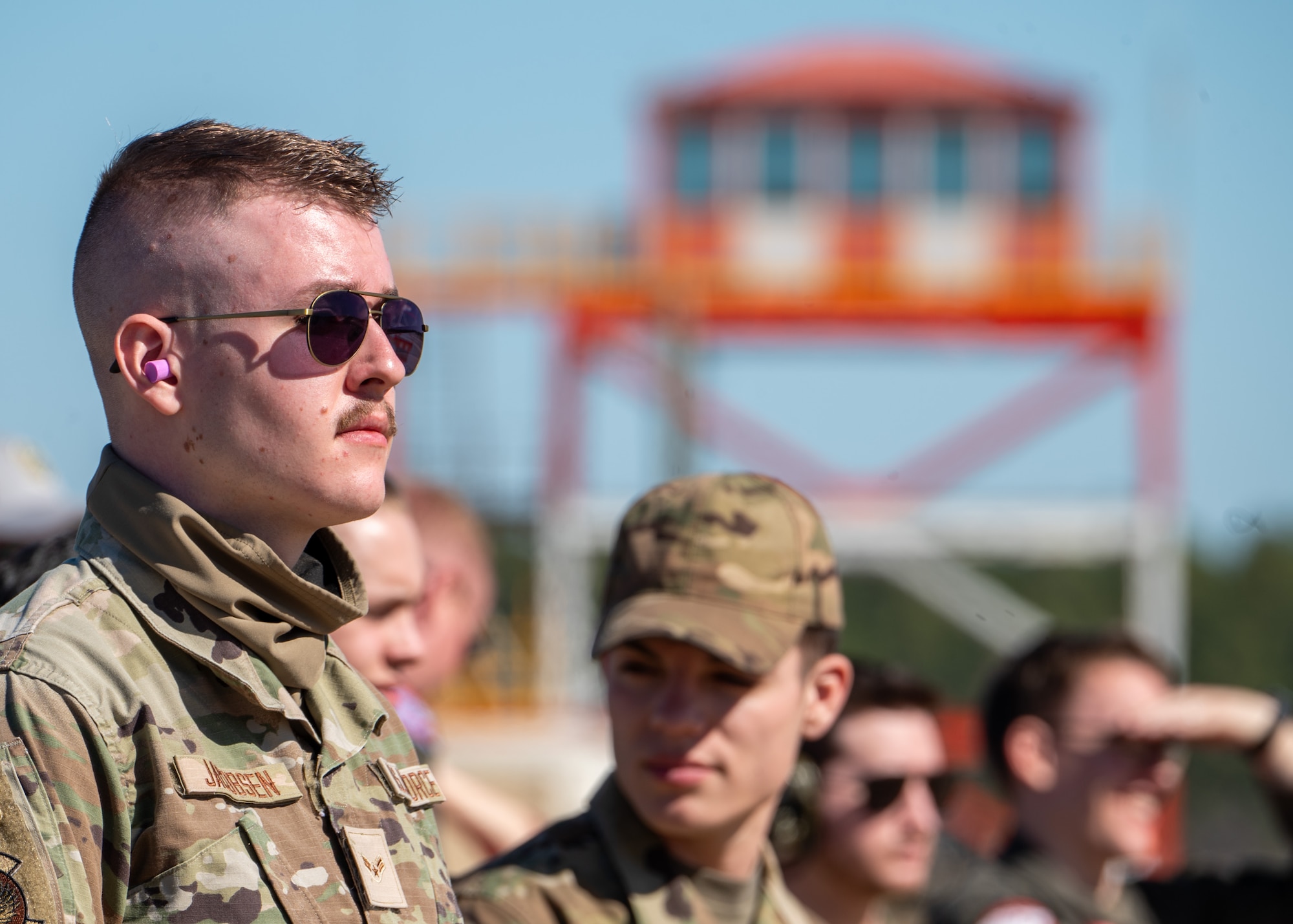 A man looks off screen at the sky, there are blurred people behind him looking as well.