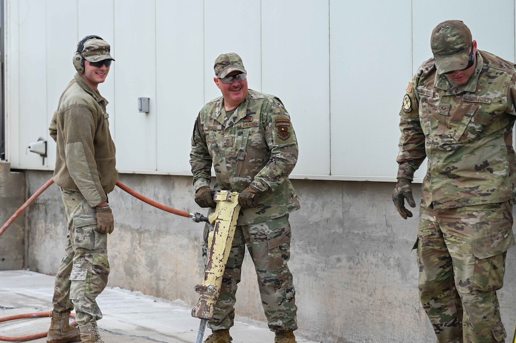 U.S. Air Force Chief Master Sgt. Justin Apticar, center, 19th Air Force command chief, uses a jackhammer at Altus Air Force Base (AFB), Oklahoma, March 12, 2024. Apticar included Altus AFB in his list of bases he wanted to visit before he retires later this year. (U.S. Air Force photo by Airman 1st Class Kari Degraffenreed)
