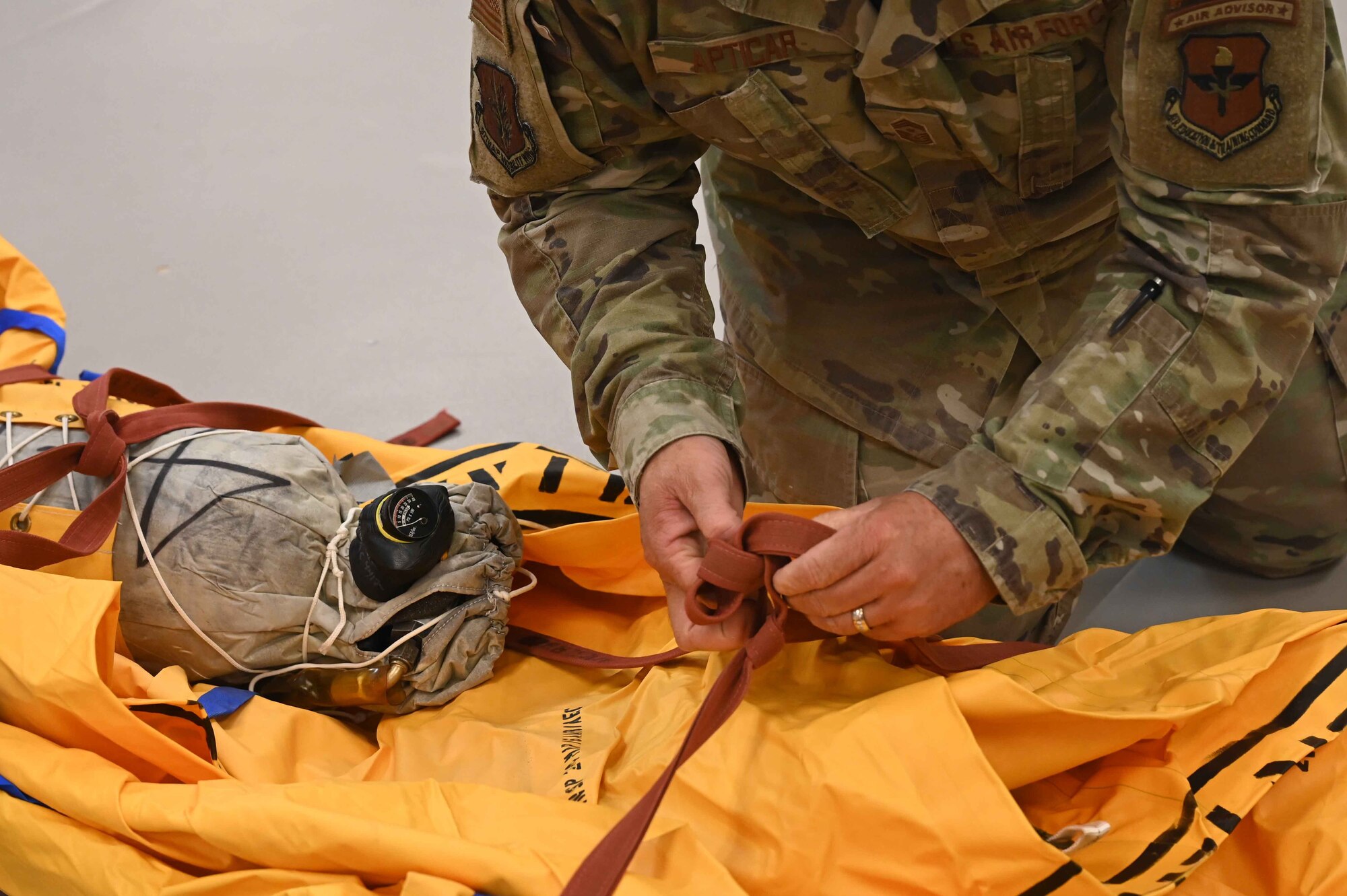 U.S. Air Force Chief Master Sgt. Justin Apticar, 19th Air Force command chief, ties off a46-person raft that he helped roll at Altus Air Force Base (AFB), Oklahoma, March 12, 2024.While meeting with Airmen of the 97th Air Mobility Wing, Apticar answered questions about his career, why he loves to come to Altus AFB, and explained the importance of Air Education Command changing to Airmen Development Command. (U.S. Air Force photo by Airman 1stClass Kari Degraffenreed)