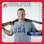 Man in Team USA shirt standing with shotgun.