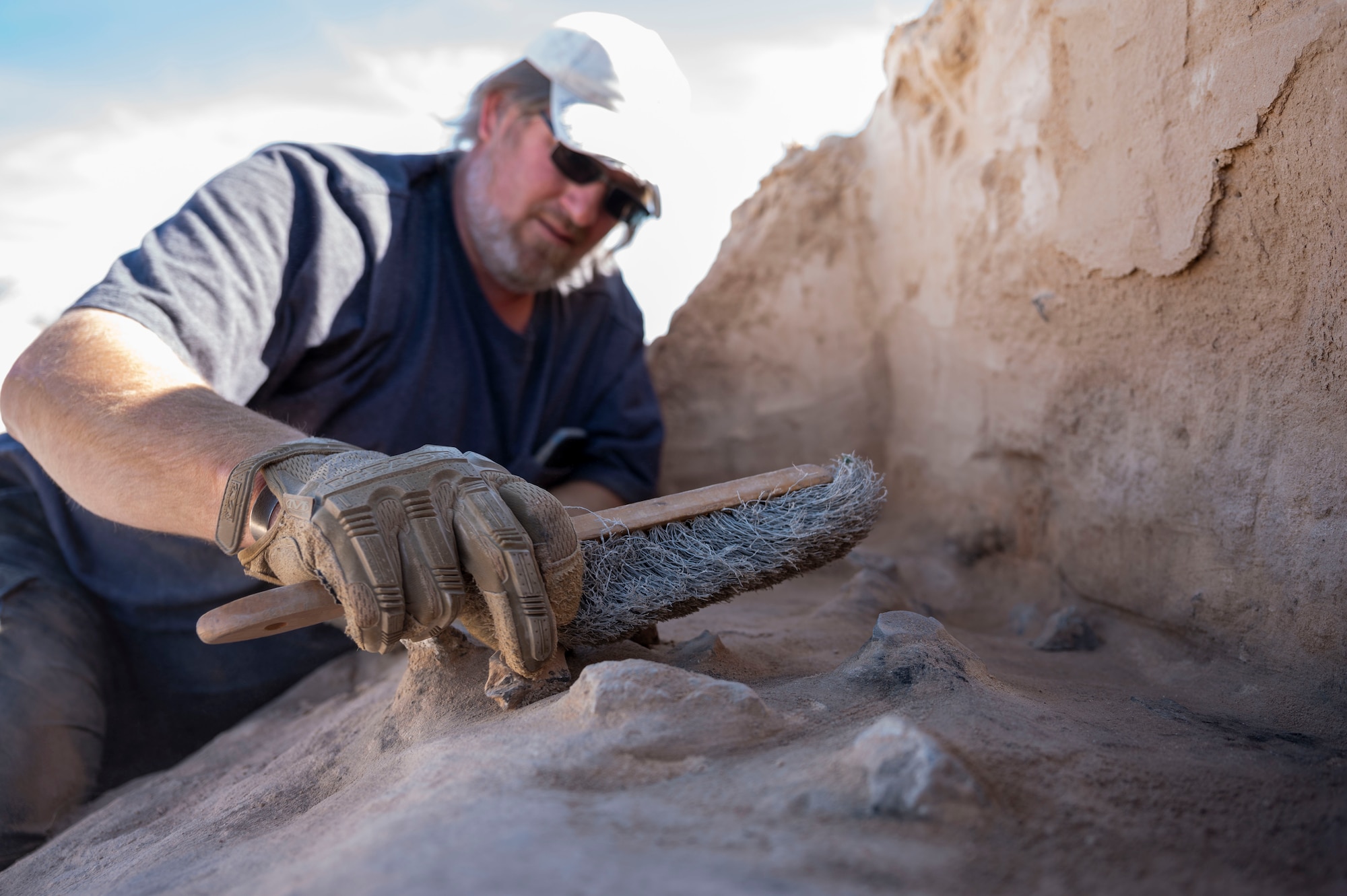 Matthew Cuba, 49th Civil Engineer Squadron cultural resource manager, brushes off the remnants of a Paleo-Archaic hearth at Holloman Air Force Base, New Mexico, Mar. 7, 2024. The site named Gomolak Overlook is believed to be approximately 8,200 years old and is one of the oldest sites uncovered in the Tularosa Basin. (U.S. Air Force photo by Airman 1st Class Isaiah Pedrazzini)