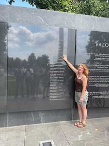 Kerry Wilkins places her hand on the name of her great uncle, Maj. Raymond H. Wilkins, while visiting the Air Force Memorial’s Medal of Honor Wall in Arlington, Va., July 2023.