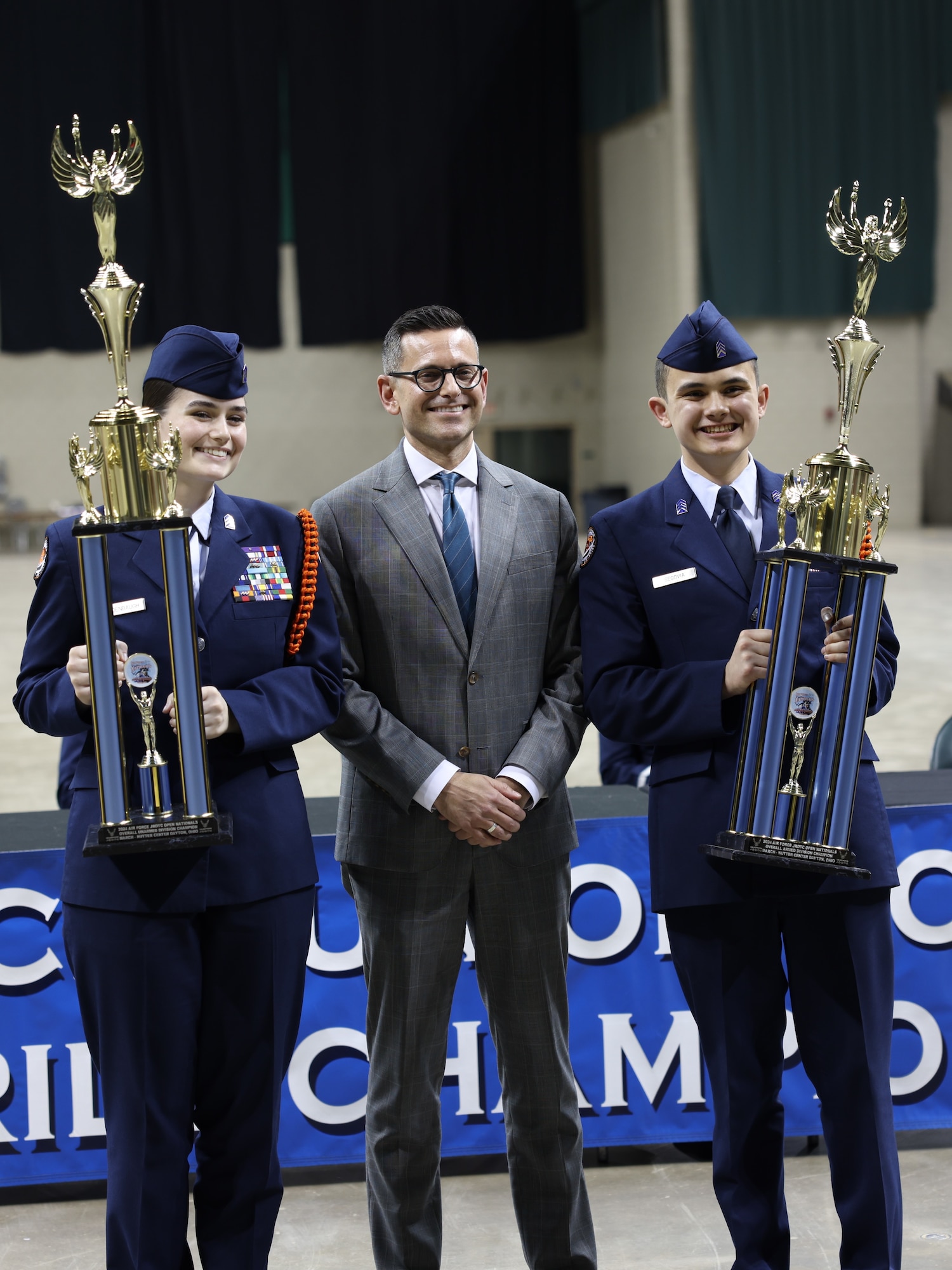 The Honorable Alex Wagner presents a coin to an Air Force Junior ROTC cadet during the Open Drill Nationals competition.