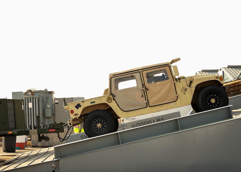 A military vehicle rides up a ramp onto a ship.