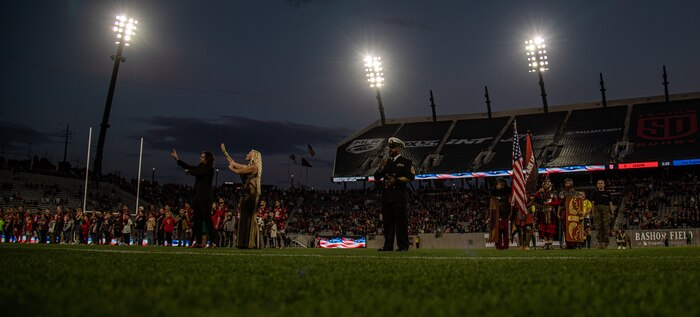 Members of the San Diego Legion color guard alongside U.S. Marine Corps Cpl. Sarah Grawcock, a combat photographer and mascot handler with Headquarters and Service Battalion, Marine Corps Recruit Depot San Diego, and Pfc. Bruno, the mascot of MCRD San Diego and the Western Recruiting Region, stand at attention during the national anthem at Snapdragon Stadium in San Diego, California, March 16, 2024. The mascot's job is to boost morale, participate in outreach work and attend events and ceremonies. (U.S. Marine Corps photo by Sgt. Jesse K. Carter-Powell)