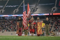 Members of the San Diego Legion color guard alongside U.S. Marine Corps Cpl. Sarah Grawcock, a combat photographer and mascot handler with Headquarters and Service Battalion, Marine Corps Recruit Depot San Diego, California, and Pfc. Bruno, the mascot of MCRD San Diego and the Western Recruiting Region, stand at attention during the national anthem at Snapdragon Stadium in San Diego, March 16, 2024. The mascot's job is to boost morale, participate in outreach work and attend events and ceremonies. (U.S. Marine Corps photo by Sgt. Jesse K. Carter-Powell)