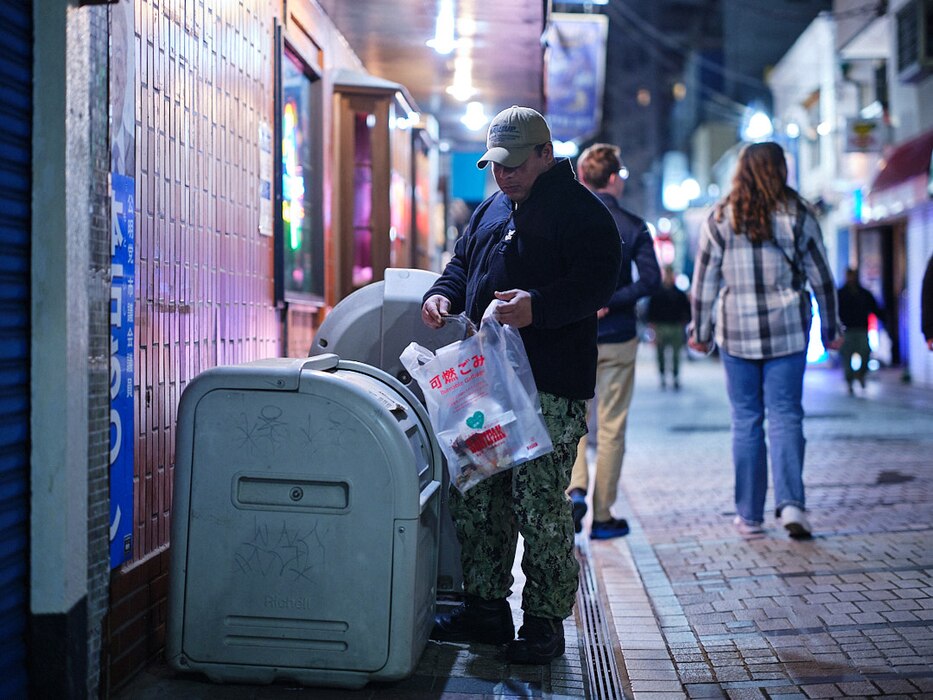 A Sailor from Naval Supply Systems Fleet Logisitics Center Yokosuka picks up trash near a bar in The Honch in Yokosuka, Japan March 15, 2024.