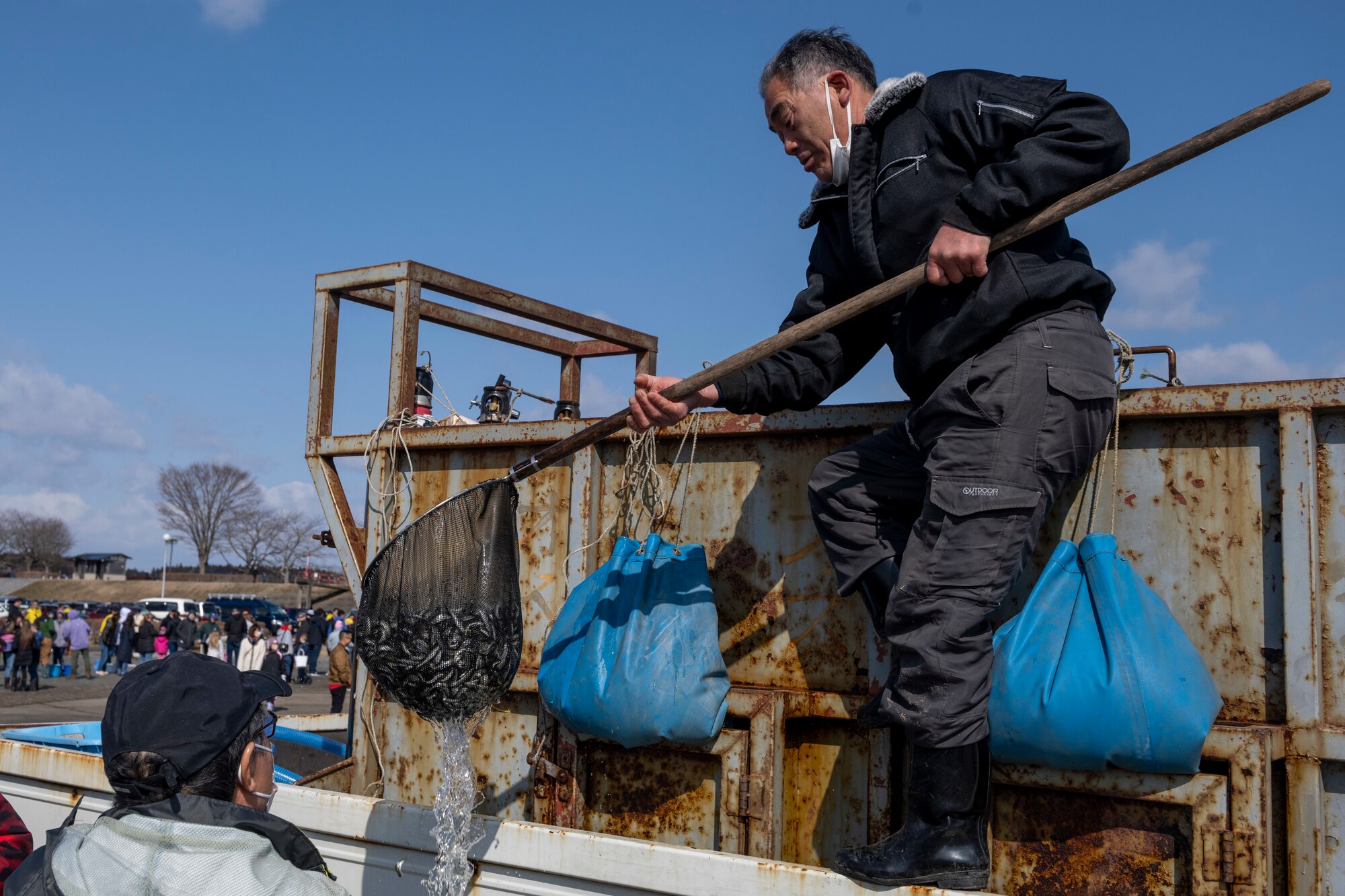 A man lowers a net full of juvenile salmon into a tub during the 25th annual Oirase Salmon Release at Shimoda Salmon Park, Japan, March 16, 2024.