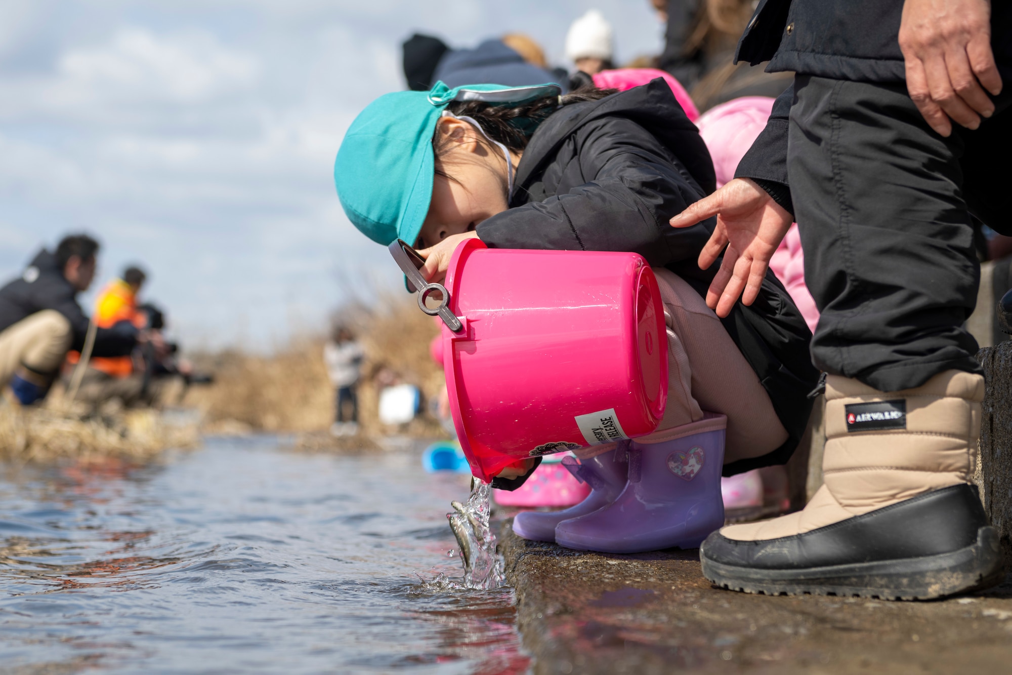 A young participant releases juvenile salmon into the Oirase River during the 25th annual Oirase Salmon Release at Shimoda Salmon Park, Japan, March 16, 2024.