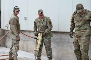 U.S. Air Force Chief Master Sgt. Justin Apticar, center, 19th Air Force command chief, uses a jackhammer at Altus Air Force Base (AFB), Oklahoma, March 12, 2024. Apticar included Altus AFB in his list of bases he wanted to visit before he retires later this year. (U.S. Air Force photo by Airman 1st Class Kari Degraffenreed)