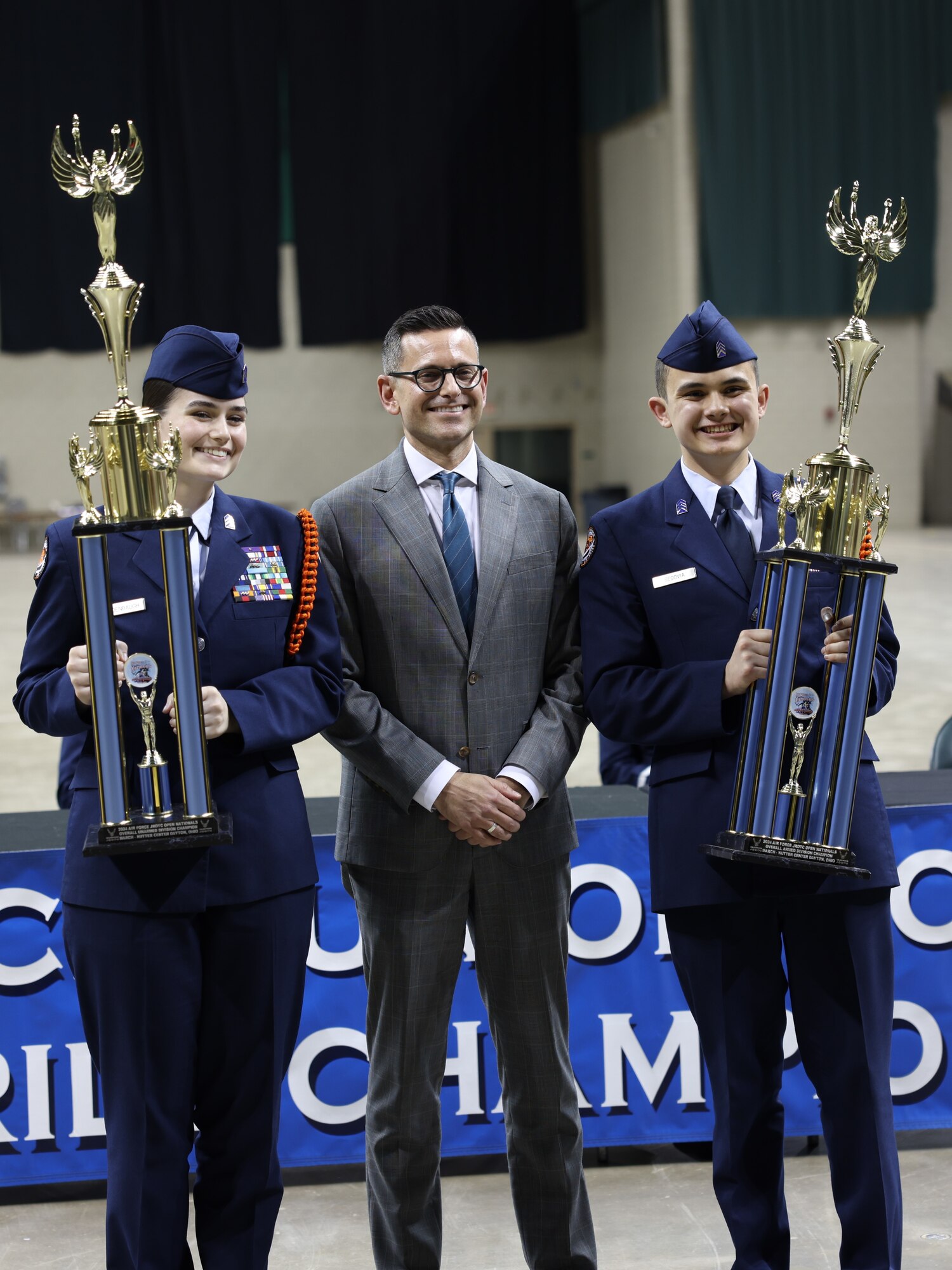 The Honorable Alex Wagner presents a coin to an Air Force Junior ROTC cadet during the Open Drill Nationals competition.