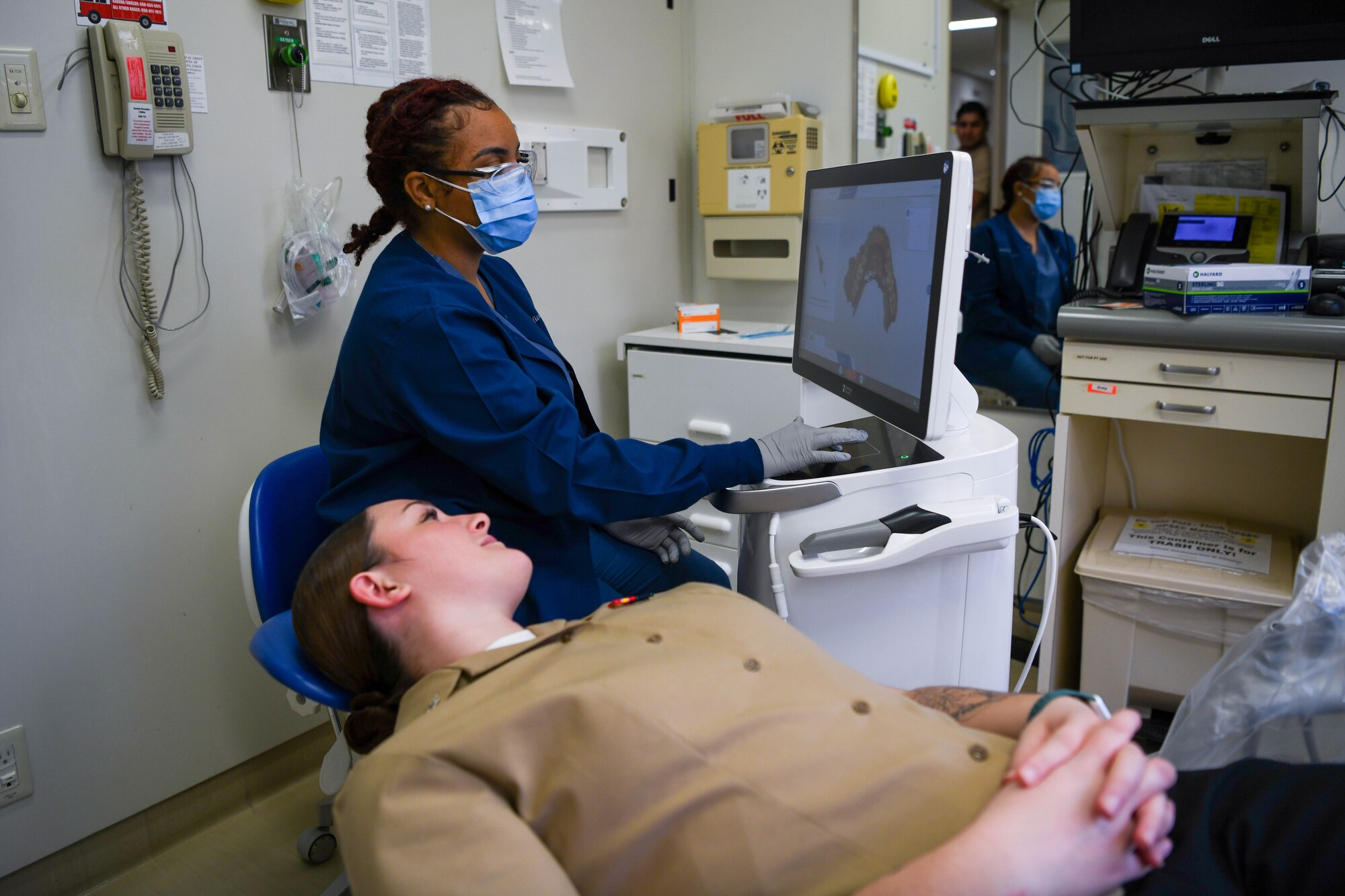 To service members look at a dental machine.