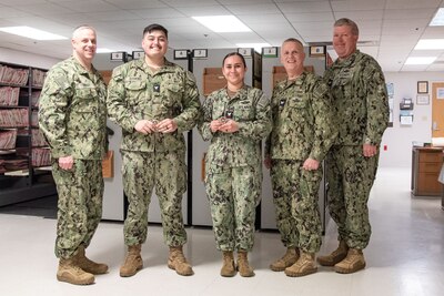 Hospital Corpsman Second Class Emily Page, center right, and Hospital Corpsman Third Class Brandon Hankins, center left, received Commander’s Coins from Navy Captain Sean Barbabella, the clinic’s Commanding Officer on Thursday, March 14, 2024.  Both serve in the clinic’s Patient Administration Department.