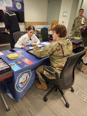 NORA optician technician U. S. Army Specialist Joanna Rodriguez, takes an order from a military member during the DHHQ Vision Readiness Day. In the background is Capt. Marc Herwitz, former executive officer and commanding officer of NOSTRA which was later renamed NORA after the Navy Medicine reorganization. Photograph by Michael Rhode, BUMED Communications Division.