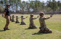 Men in U.S. Army uniforms firing pistols on outdoor pistol range.