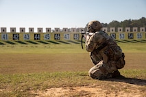 Soldier in U.S. Army uniform firing weapon on outdoor rifle range.
