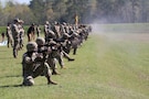 Multiple men in U.S. Army uniforms on outdoor rifle range.