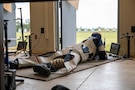 Man in shooting uniform in prone position with air rifle.