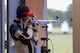 Woman in shooting uniform standing with air rifle.