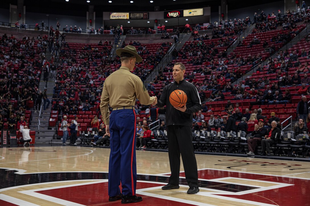 U.S. Marine Corps Sgt. Seth Wilson, a drill instructor with Lima Company, 3rd Recruit Training Battalion, presents the game ball as Hero of the Game to Scott Brown, a referee for the San Diego State University Basketball game at SDSU, California, Feb. 27, 2024. The Hero of the Game is to recognize and feature a veteran or an active-duty member of our military for their heroic service. (U.S. Marine Corps photo by Lance Cpl. Sarah M. Grawcock)