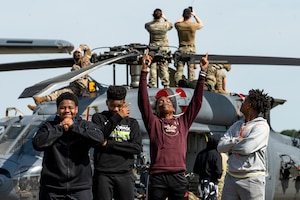 Group of children standing in front of a helicopter