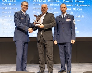 From left: Maj. Gen. Scott Cain, Air Force Research Laboratory commander; Yosef Hassan, AFWERX Contracting Division head; and Chief Master Sgt. Carlos E. Labrador, AFRL command chief, stand for an award presentation during the 2023 Annual Awards Ceremony March 19, 2024, at the Air Force Institute of Technology's Kenney Hall at Wright-Patterson Air Force Base, Ohio. Hassan accepted the Mission Support Team Award for the AFWERX contracting team. (U.S. Air Force photo / Keith Lewis)