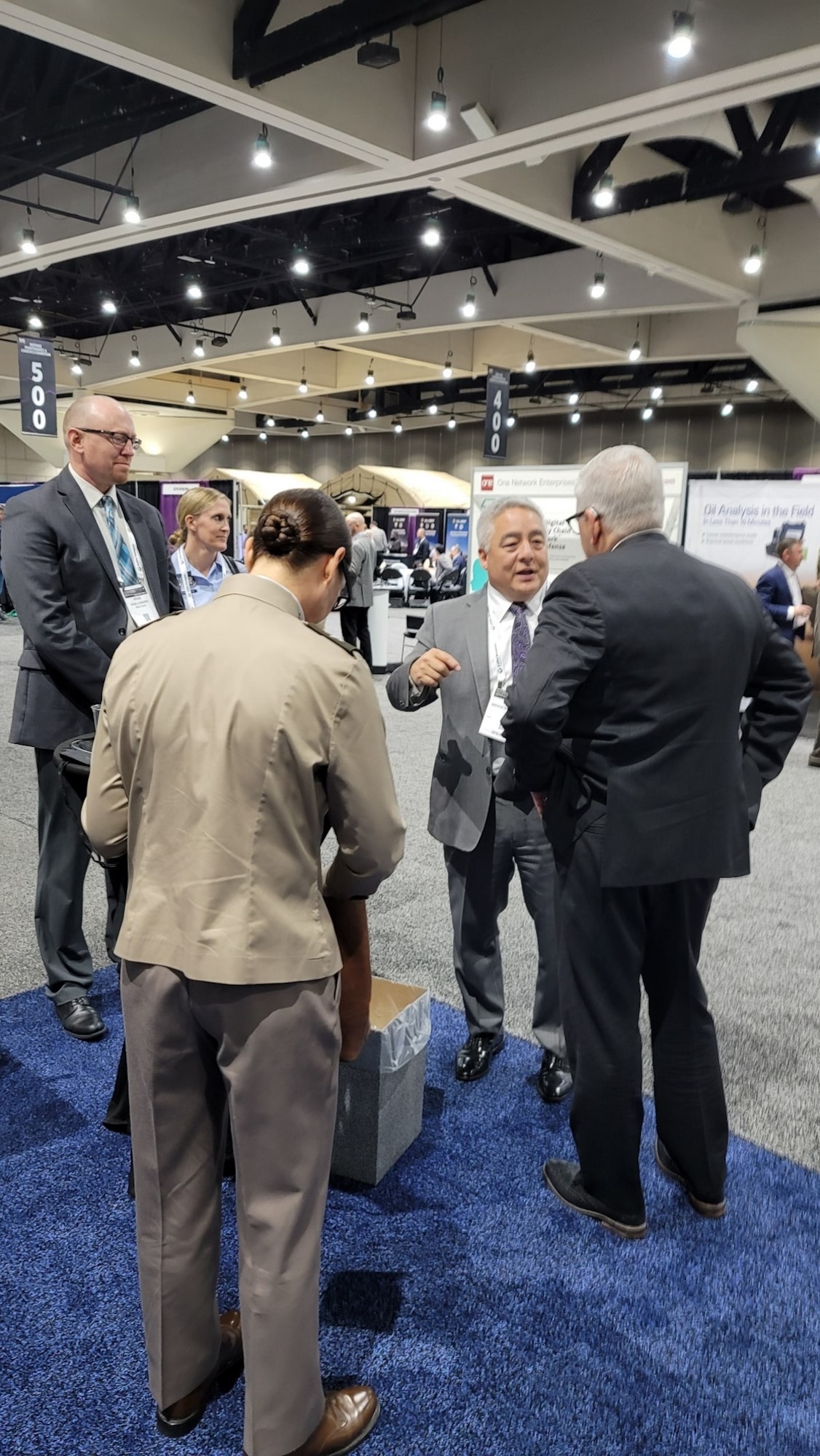 Brad Leonard, Director SSC/S4 (far left), United States Space Force Associate Chief Operations Officer Bruce Hollywood (middle/grey suit), Assistant Secretary of Defense Hon. Christopher Lowman (far right/dark grey suit) discuss US Space Force maintenance planning.