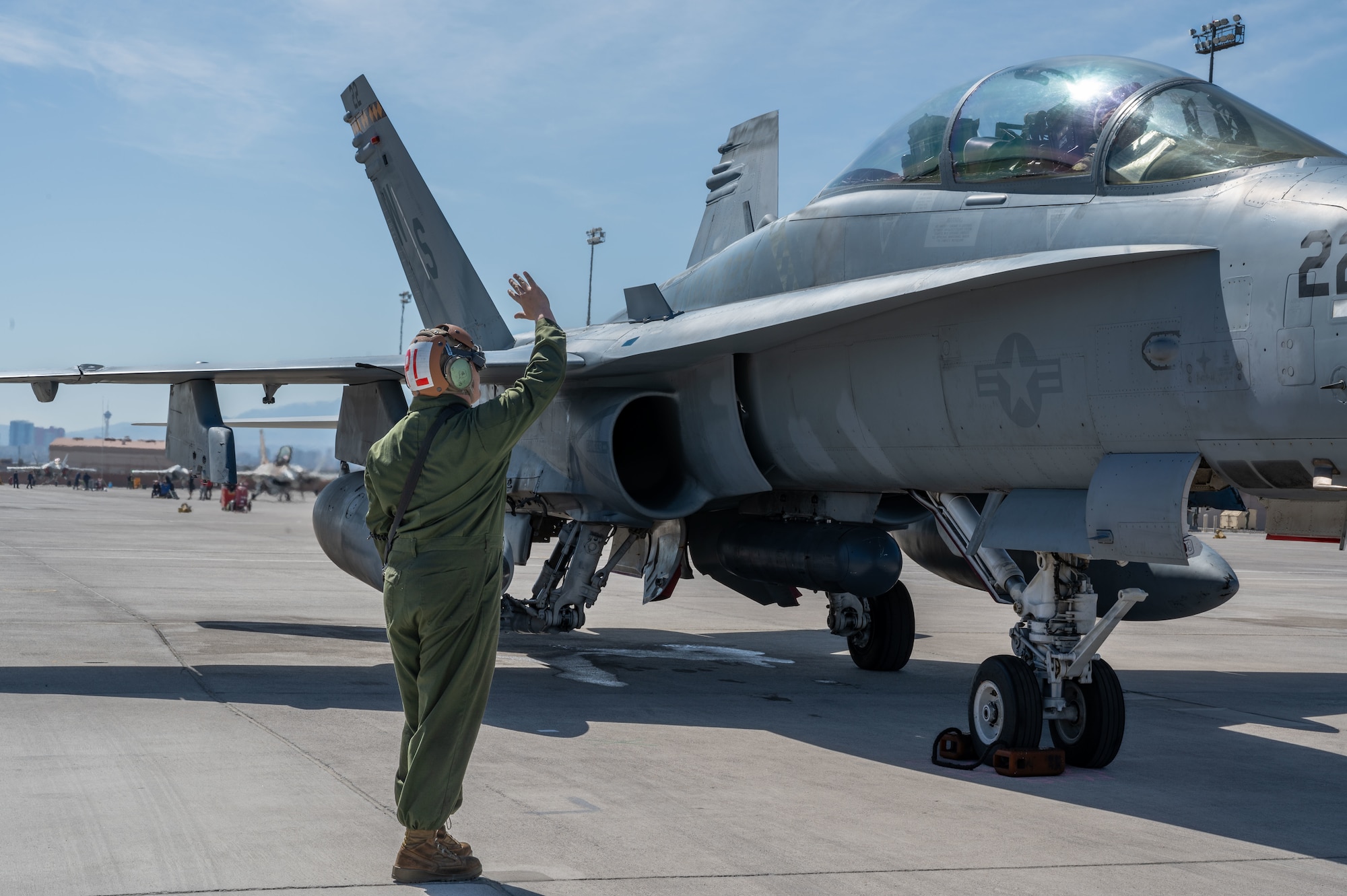 U.S. Marine Corps Lance Cpl. Andrew Garcia, a Marine Fighter Attack Squadron (VMFA) 323 fixed wing aircraft head plane captain, Marine Corps Air Station, Miramar, California, communicates with a pilot before the launch of an F/A-18C Hornet during Red Flag-Nellis 24-2 at Nellis Air Force Base, Nevada, March 11, 2024.