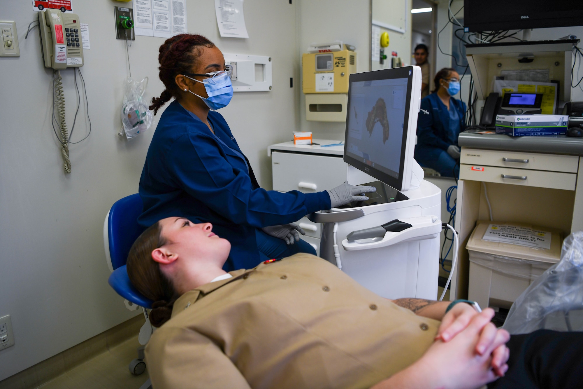 To service members look at a dental machine.