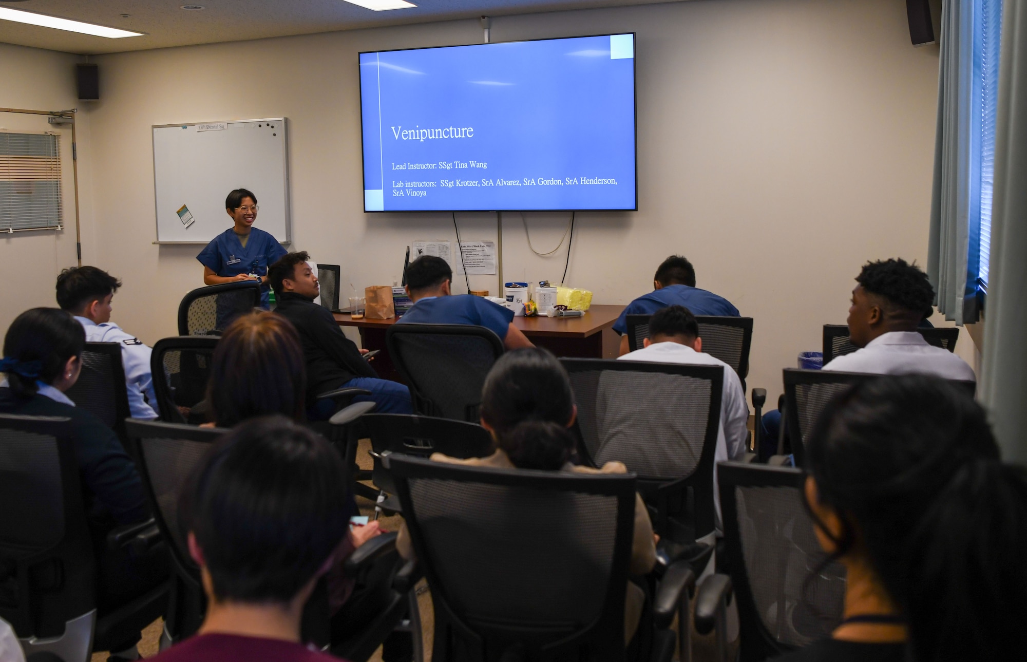Service members and civilians participate in a lecture.