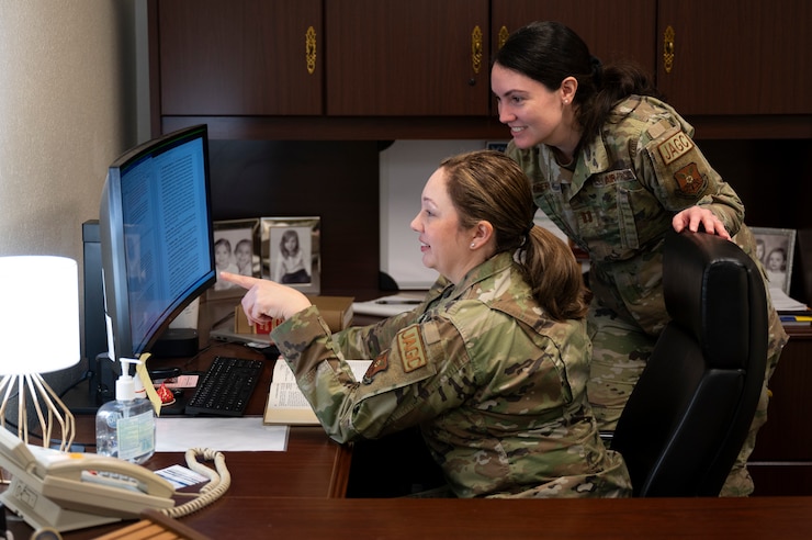 Two female U.S. Airmen look at a computer screen