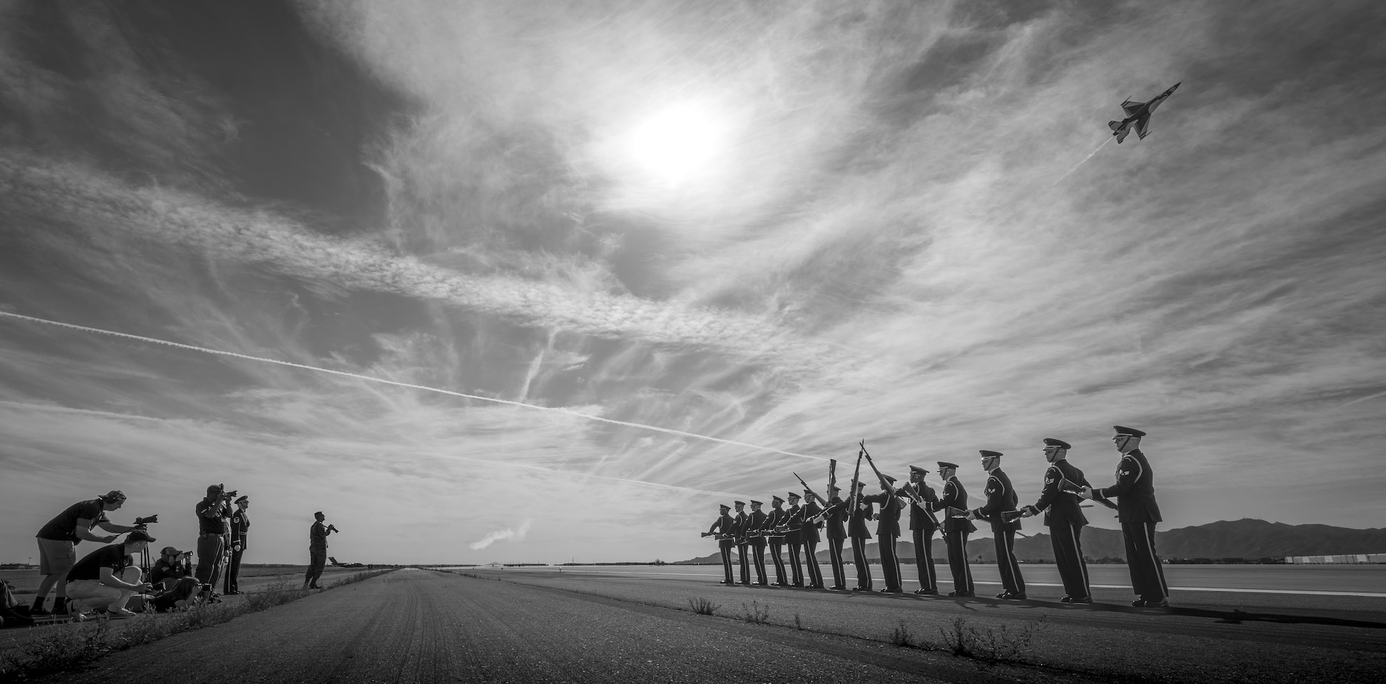 The U.S. Air Force Honor Guard practices a formation as an F-16 Fighting Falcon, assigned to the U.S. Air Force Demonstration team, the "Thunderbirds," pass behind them prior to Luke Days 2024 on March 22, 2024, at Luke Air Force Base, Arizona.